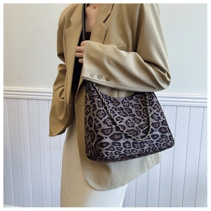 Détail du sac à bandoulière léopard avec chaîne dorée porté par un mannequin chic