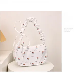 Detail of white floral scrunchie strap hobo bag with bow tie and printed art text