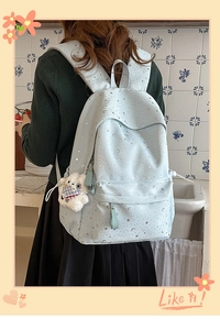 Detail of light blue backpack with star patterns and a small white bear plush charm