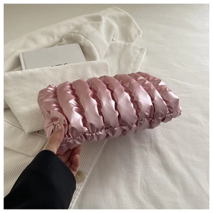 Detailed view of pink metallic ruched clutch bag with soft pleated glossy fabric texture