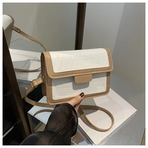 Detail of white crocodile texture leather crossbody bag with brown trim and metal clasp