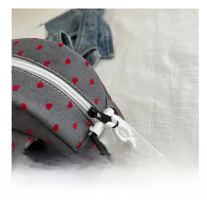 Gros plan sur une fermeture éclair blanche fluide d'un sac en toile gris à motifs de cœurs
