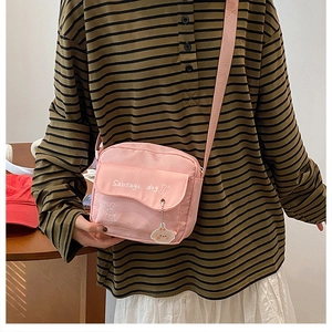 Detail of pink canvas crossbody bag featuring sausage dog embroidery and cute charm