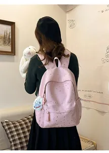 Detailed view of a pink starry schoolbag for girls with a white plush bunny charm