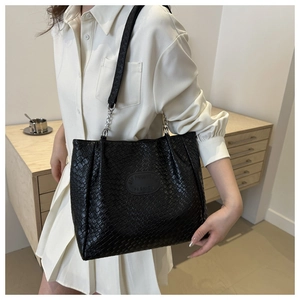 Close-up of black quilted weave pattern and metallic chain detail on tote shoulder bag