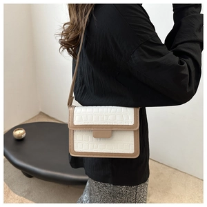 Detail of elegant white crocodile pattern crossbody bag with khaki trim worn by model