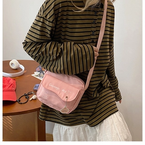 Detail of pink canvas crossbody bag featuring white sausage dog print and metal pendant