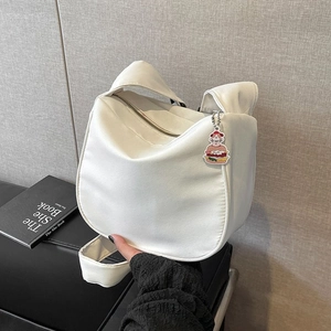 Détail d'un sac bandoulière blanc avec bandoulière plissée et charm en forme de burger