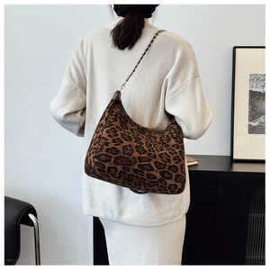 Détail d'un sac hobo léopard avec bandoulière en chaîne dorée porté par un mannequin