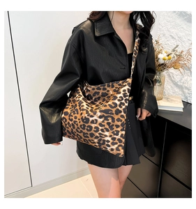 Detail of stylish leopard print canvas tote bag with wide strap on model in leather jacket