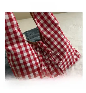 Detailed close-up of red and white gingham fabric bag with a decorative ribbon tie