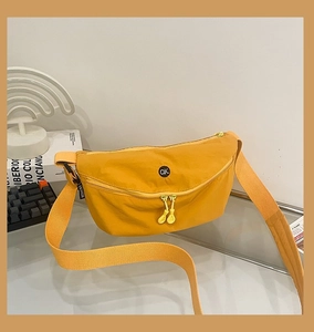 Detailed macro view of ginger yellow nylon bag with circular OK logo and fashion label