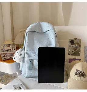 Detail of light blue star pattern backpack with plush bear charm and tablet for size scale