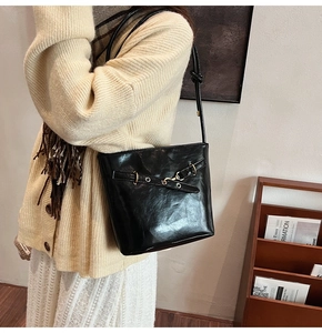 Gros plan sur un sac fourre-tout noir brillant avec sangle à œillets et texture souple