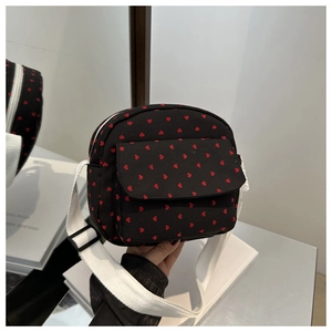 Détail de la sacoche en toile noire avec motif cœurs rouges et bandoulière ajustable