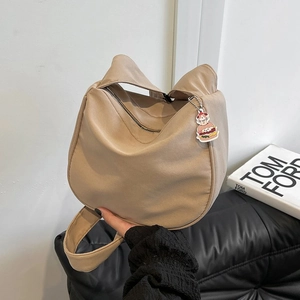 Gros plan d'un sac dumpling en toile beige avec un porte-clés personnage hamburger mignon