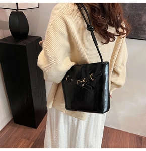 Détail du sac à bandoulière noir brillant avec boucle en métal et sangle en cuir