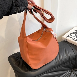 Détail du sac dumpling orange vif avec bandoulière confortable et pendentif lapin mignon