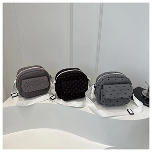 Vue détaillée des sacs bandoulière en toile avec motifs cœurs et pois sur un socle moderne