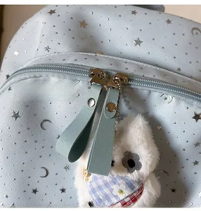 Detail of blue star print backpack featuring silver double zippers and a plush puppy charm