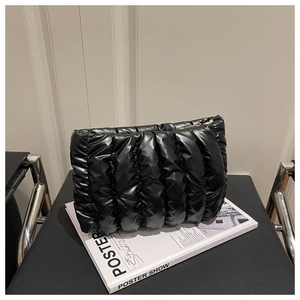 Detailed macro view of black quilted puffer bag with glossy PU texture and gold zipper