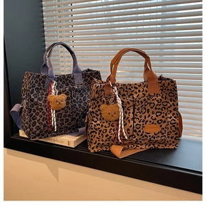Detail of leopard print tote bags with multi-pockets, sturdy handles, and bear charm accessories