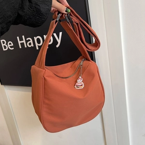 Détail du sac orange minimaliste avec bandoulière réglable et breloque burger mignonne