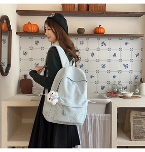 Close-up of light blue star and moon pattern backpack with a cute plush bear charm