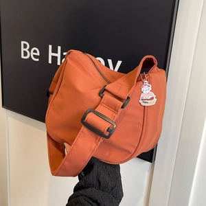 Détail du sac bandoulière orange avec sangle large et pendentif chat mignon décoratif