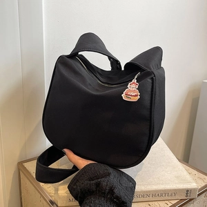 Détail du sac en toile noire en forme d'oreilles de chat avec breloque hamburger