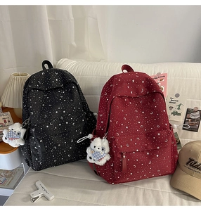 Close-up of star pattern school backpacks in black and burgundy with cute bear charms