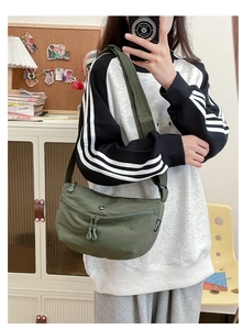 Close-up of military green crescent nylon bag with adjustable strap and dual zippers