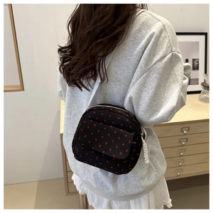Détail d'un sac en toile noire avec motifs de cœurs rouges et bandoulière blanche
