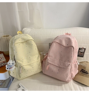 Detail of light yellow and pink star-patterned backpacks on a white sofa