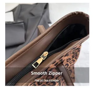 Detail view of the smooth black metal zipper and leopard print fabric on a tote bag