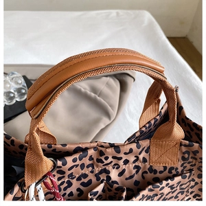 Detail of leopard print tote bag showing leather handles and premium fabric texture