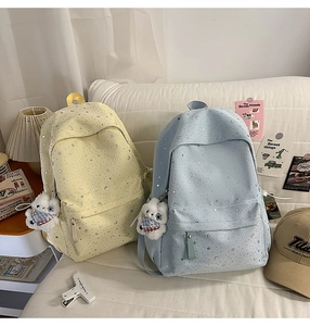 Detail of yellow and blue backpacks with star moon prints and plush puppy pendants