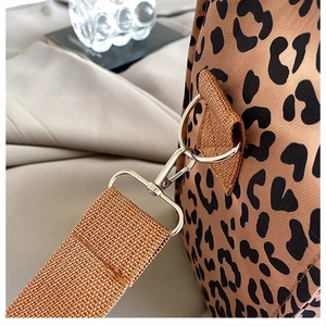 Macro detail of leopard print tote featuring silver metal hook and woven shoulder strap