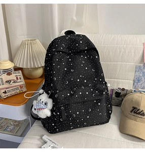 Detail of black star and moon pattern canvas backpack with a cute white plush bear pendant