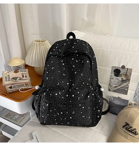 Detail of black canvas backpack featuring white star moon prints on a white sofa