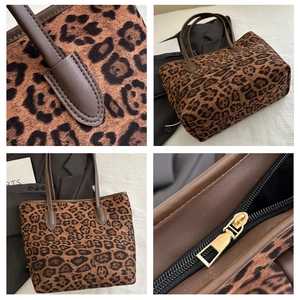 Detail of leopard print tote bag showing gold metal zipper and leather handle