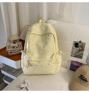 Lifestyle shot of yellow star pattern backpack on white sofa with cozy room decor