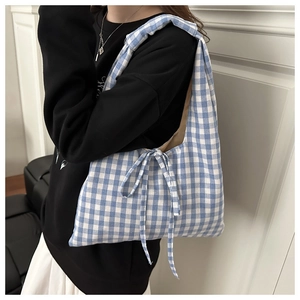 Detail view of a blue and white checkered tote bag featuring a decorative side bow knot