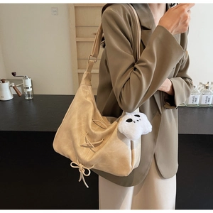 Dettaglio della borsa tote oversize beige in pelle a pieghe con charm a forma di panda