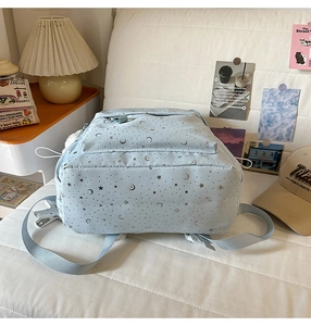 Detail of light blue backpack featuring silver star and moon patterns on fabric
