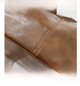 Macro view of brown leather tote bag showing double stitching and textured finish