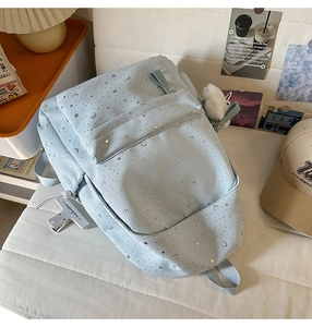 Close-up of the light blue starry backpack with silver star patterns and a fluffy white pompom
