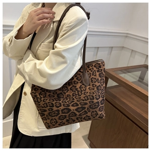 Detailed side view of a leopard print tote bag with brown straps worn by a model