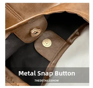 Detail view showing the magnetic snap hardware and premium leather texture of the brown tote bag