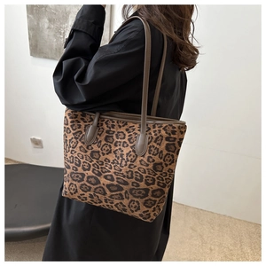 Detail view of large leopard print tote bag featuring brown leather trim and twin handles